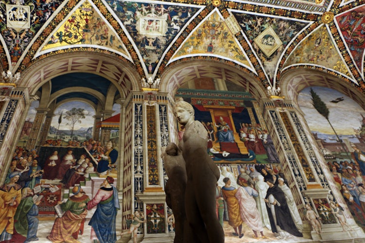Scene of Enea Silvio Piccolomini's life in frescoes in background